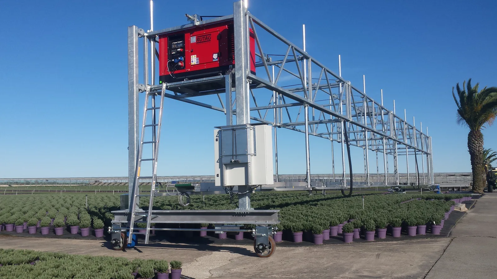 Overgewaswagen met rode bedieningskast boven een veld met potplanten