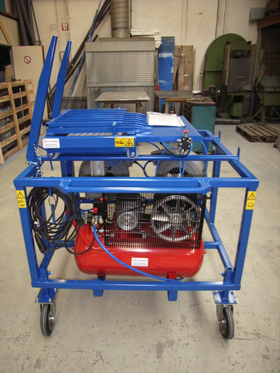 Trededrukker op een blauw verrijdbaar frame met rode compressor